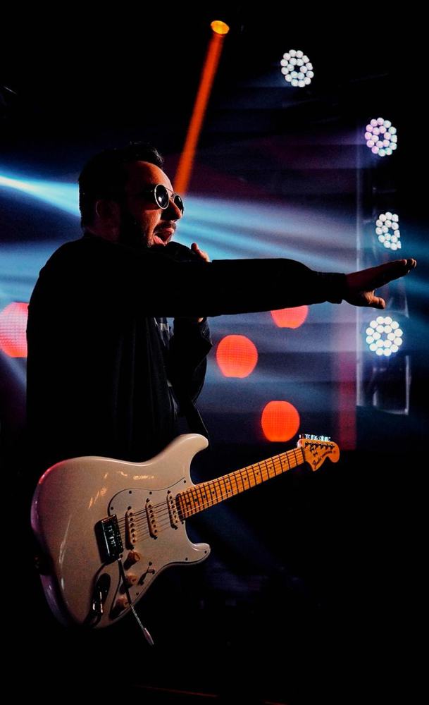 Léo Santos em silhueta com guitarra branca